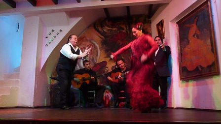 Flamenco dancer in red dress with two singers and two guitar players in background