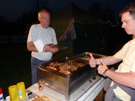 A man cooking food on a grill with a customer in front of him