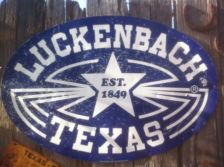 Blue sign with white letters sayindg, "Luckenbach Texas, Est. 1849"