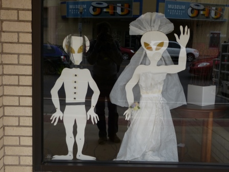 White coloured male and femaile aliends made of paper in a window dressed as newlyweds